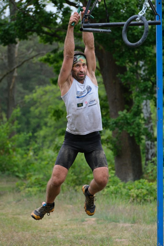 A man engaged in a challenging outdoor obstacle course race, demonstrating strength and determination.