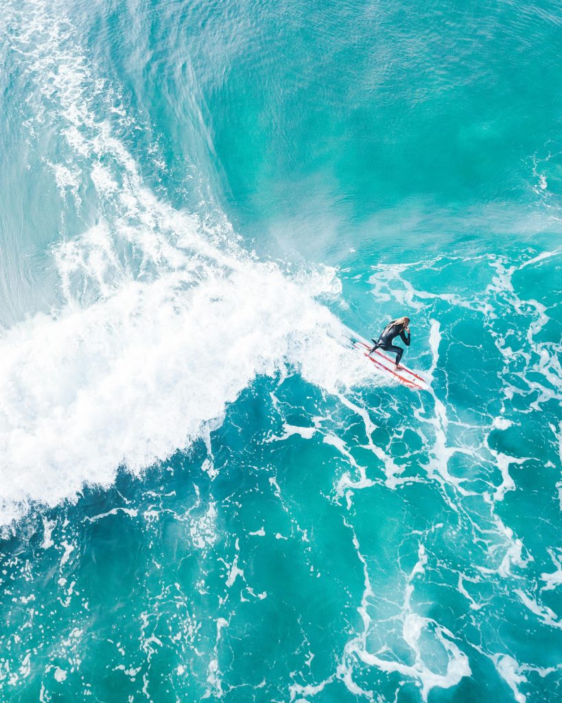 A thrilling aerial shot capturing a surfer expertly navigating turquoise ocean waves.